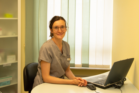 Portrait von Ella Grosch am Behandlungszimmertisch sitzend